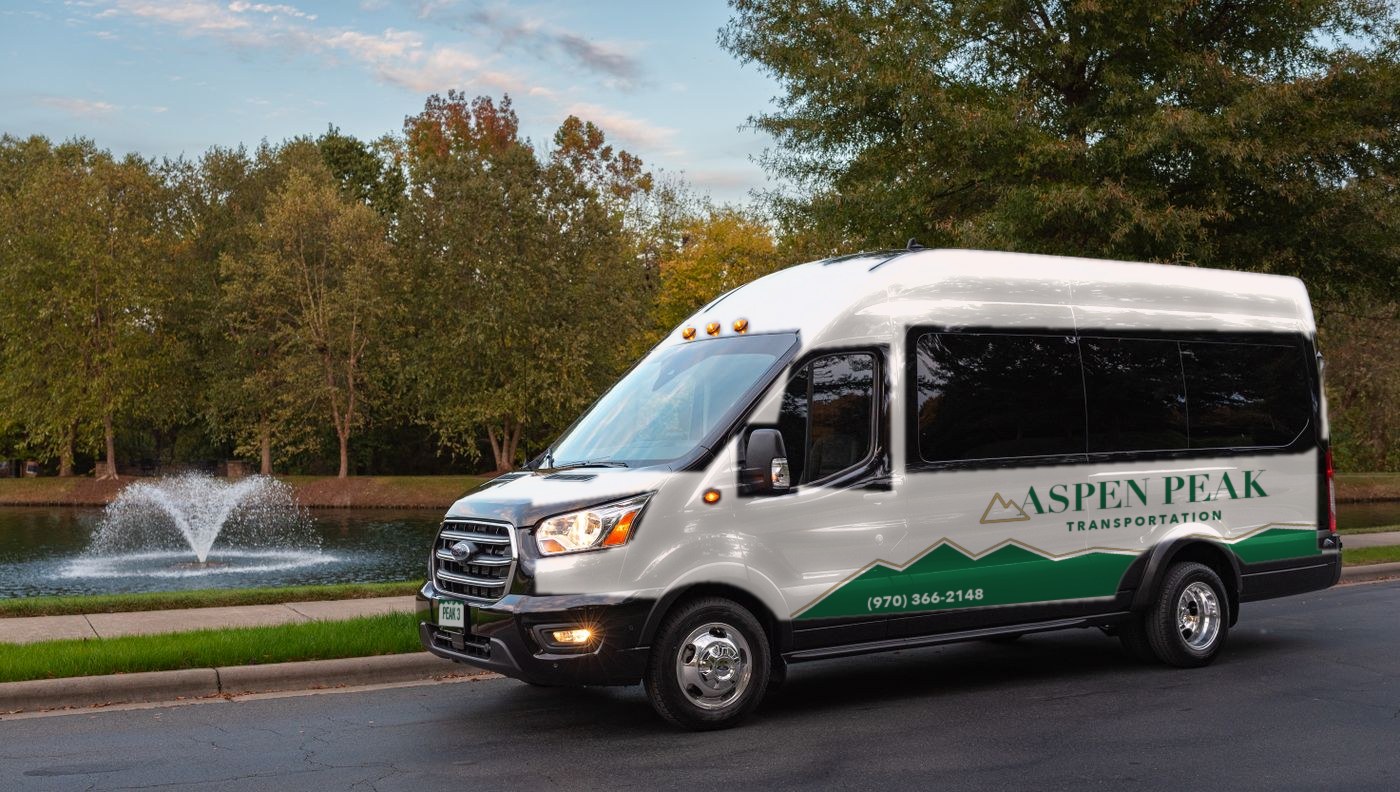 White Ford Transit passenger van with green Aspen Peak livery and plate PEAK 3